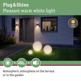 Three white plastic globe lights with warm white glow on lawn in front of modern house
