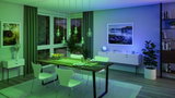 Modern dining room with wooden table, white chairs and green LED pendant lights for ambient lighting