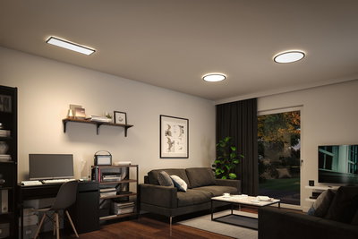 Modern living room with black furniture and three white LED ceiling lights providing ambient lighting