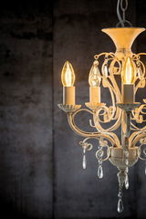 Antique white metal chandelier with warm LED candle bulbs and crystal pendants for ambient lighting