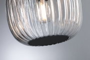 Close-up of a clear ribbed glass lamp with visible bulb and black base, modern lighting design