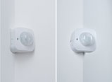 White plastic motion sensor mounted on indoor corner for automated lighting control