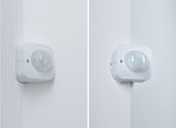 White plastic motion sensor mounted on indoor corner for automated lighting control
