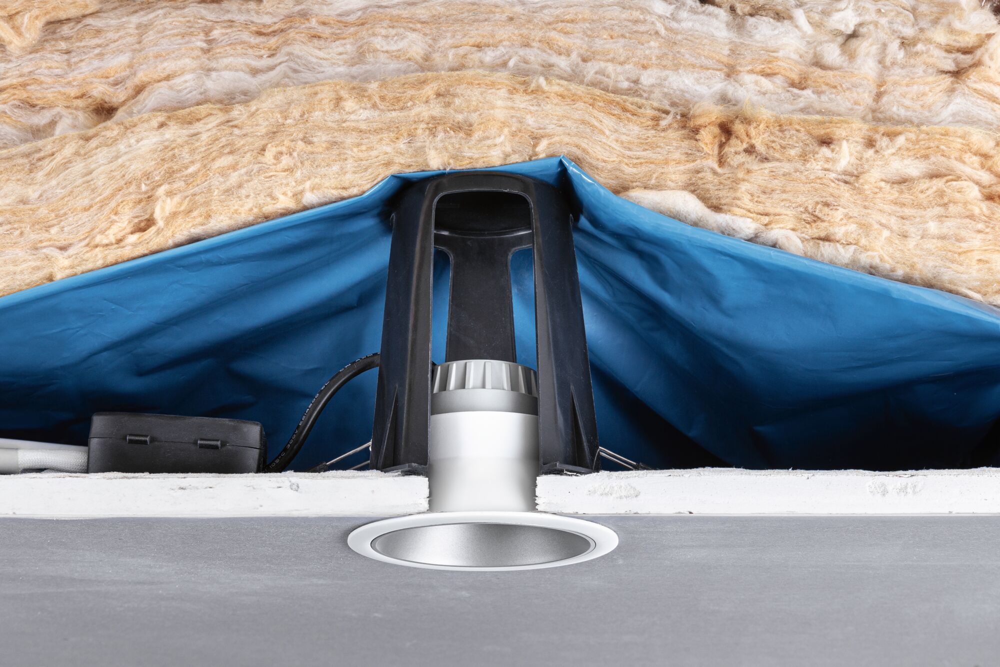Recessed LED spotlight with white frame, black bracket, and insulation in ceiling cavity