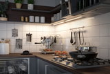 Cuisine moderne avec plan de travail en bois, cuisinière à gaz en acier inoxydable, poêle noire et éclairage LED sous meuble.