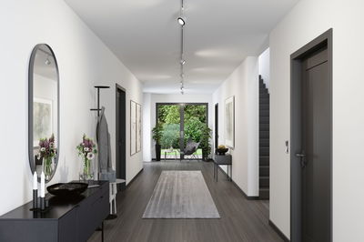 Moderner Flur mit grauem Boden, weißen Wänden, schwarzer Garderobe und LED-Schienenstrahlern an der Decke