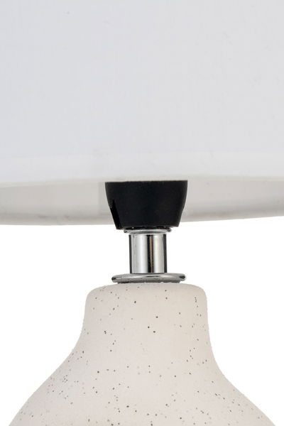 Close-up of white ceramic lamp with black speckles and chrome metal part for indoor lighting
