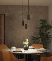 Trois suspensions noires en métal au-dessus d'une table ronde avec chaises marron et vase à fleurs