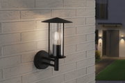 Schwarze Außenwandleuchte aus Metall mit klarem Glas und sichtbarer LED-Glühbirne an Hauswand