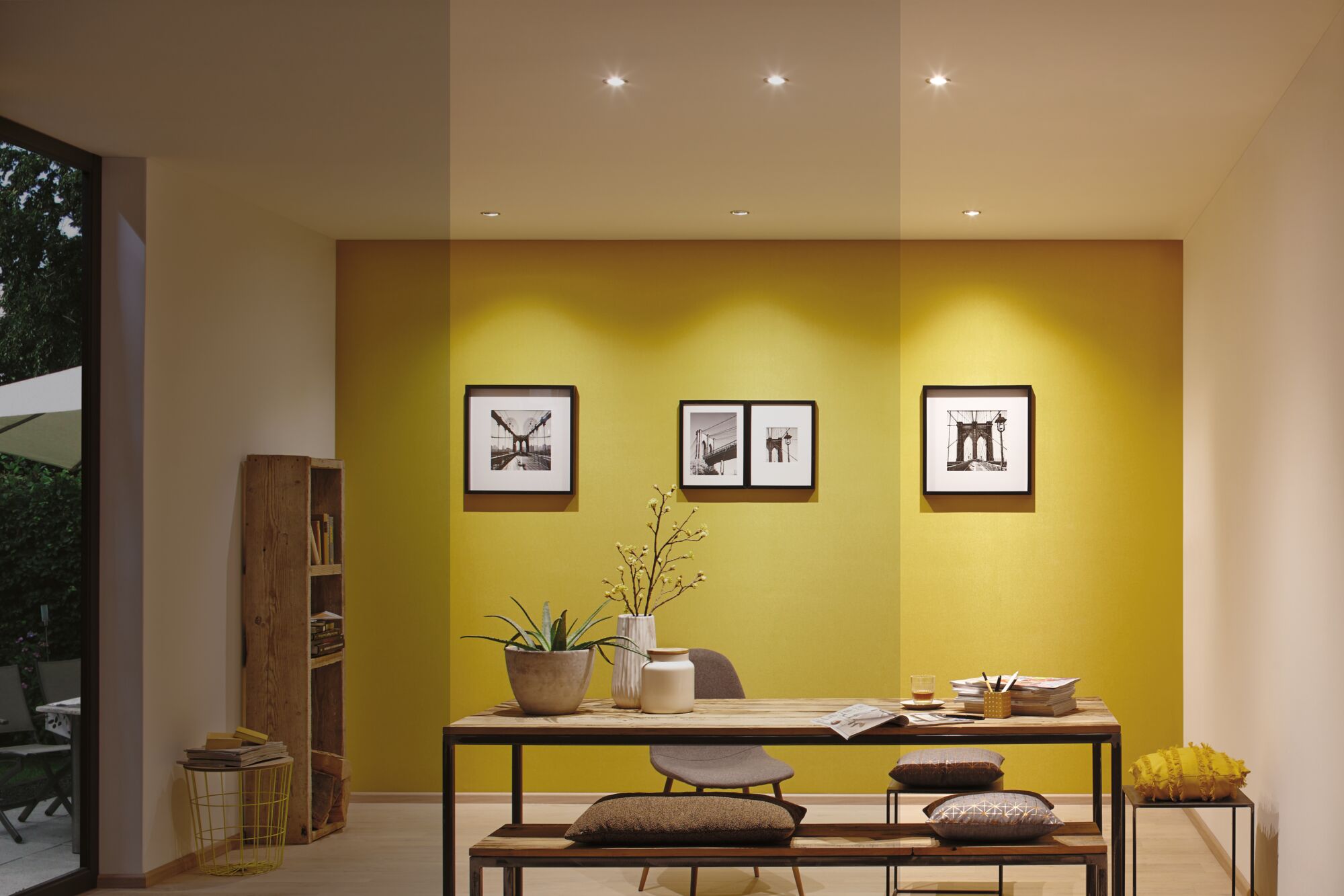Modernes Esszimmer mit gelber Wand, Holz-Tisch, Bank, Stuhl und dekorativen Kissen für Wohnraumgestaltung
