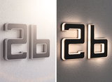 Modern house number 2b in black material with white LED lighting on wall shown day and night