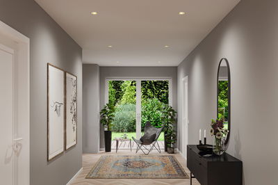 Modern hallway with grey walls, patterned rug, black sideboard and recessed LED spotlights in ceiling