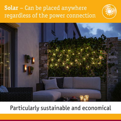 Solar outdoor lights on green hedge with cozy patio sofa at dusk, sustainable garden lighting