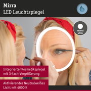 Frau trägt roten Haarband und benutzt Mirra LED Leuchtspiegel mit neutralweißem Licht zum Wimperntuschen