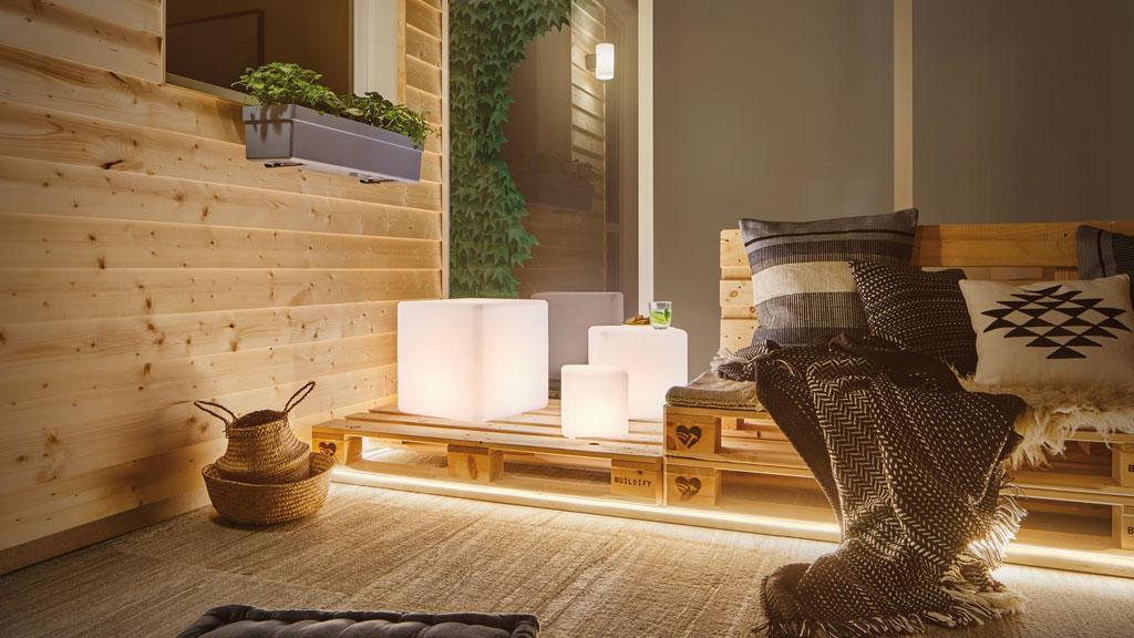 Gezellige balkonverlichting met warmwitte LED-lampen op houten pallet en moderne buiteninrichting.