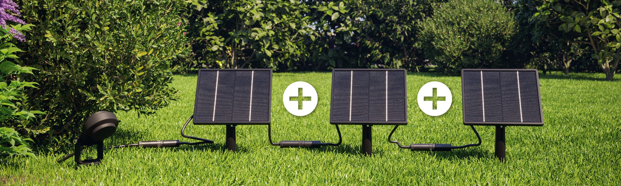 Three black solar panels on green grass with plus signs, sustainable solar energy for garden use