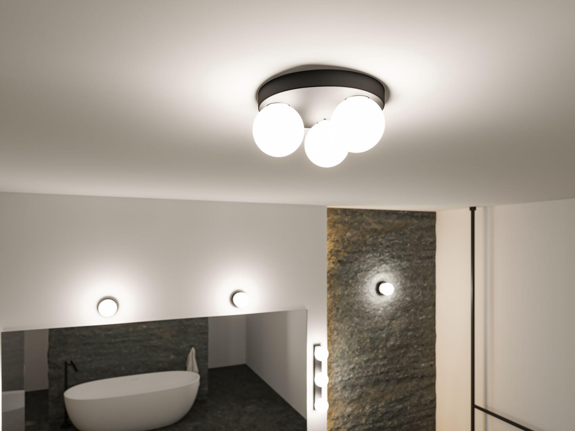 Moderne plafondlamp met vier witte glazen bollen en zwarte metalen ring in stijlvolle badkamer.