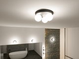 Modern ceiling light with three white glass globes and black metal ring in stylish bathroom with bathtub
