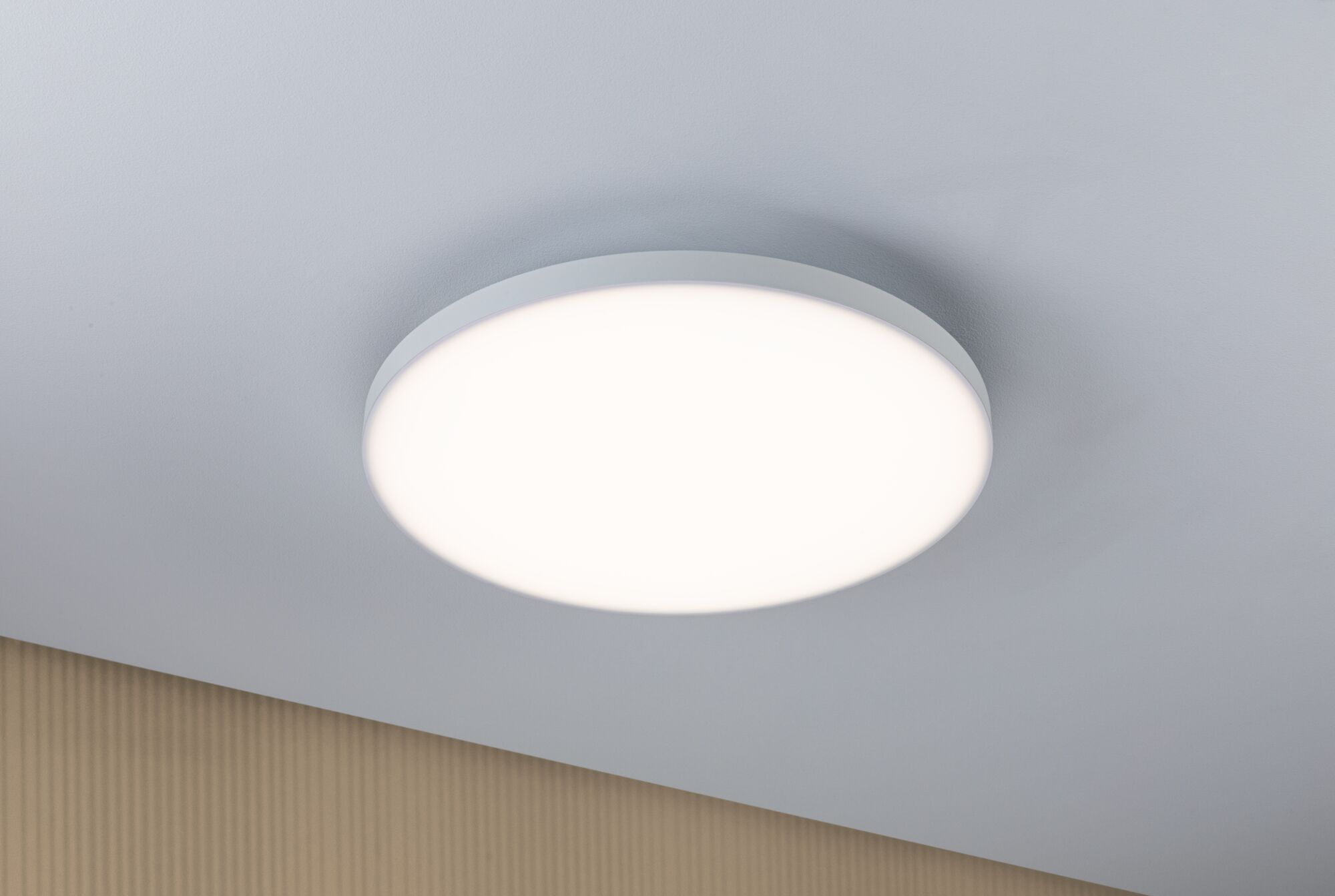 Runde weiße LED-Deckenleuchte mit mattem Rahmen an grauer Decke für modernes Raumlicht