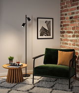 Black floor lamp with two adjustable spotlights in modern living room with green velvet armchair