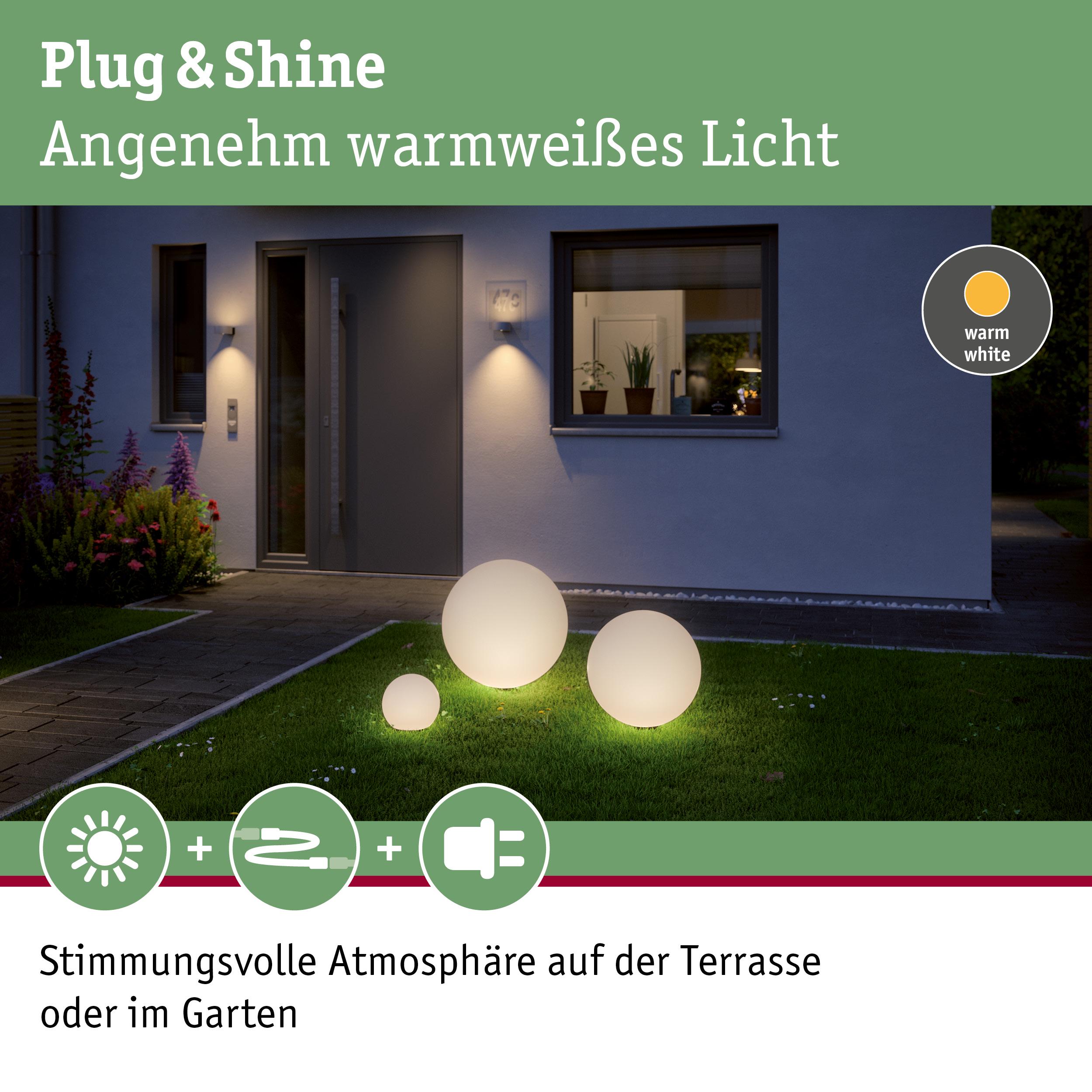 Drei weiße Kugelleuchten aus Kunststoff mit warmweißem Licht auf grünem Rasen vor modernem Haus