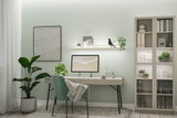 Modern home office with green fabric chair, light desk, and LED wall shelf lighting for workspace setup.