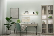 Modernes Home-Office mit grünem Stoffstuhl, hellem Schreibtisch und LED-Wandregalbeleuchtung für Arbeitszimmer.