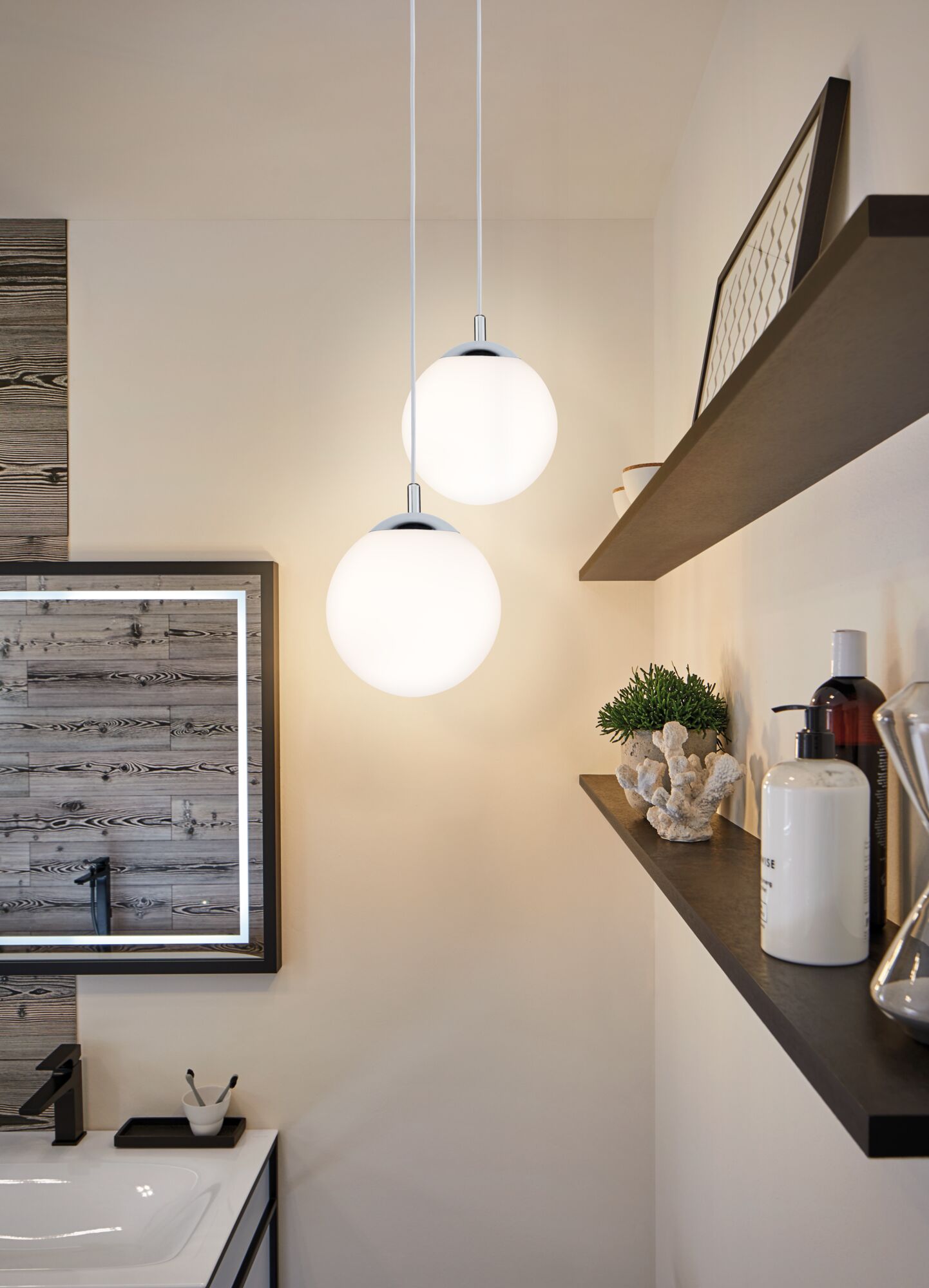Deux suspensions sphériques blanches avec éléments chromés dans une salle de bain moderne au design bois.