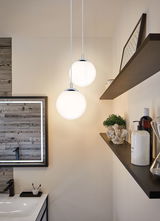 Deux suspensions sphériques blanches avec éléments chromés dans une salle de bain moderne au design bois.