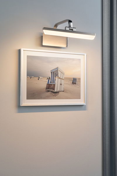 Modern brushed metal wall lamp with warm white LED light above a beach chair photo.