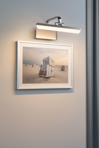 Applique murale moderne en métal brossé avec lumière LED blanc chaud au-dessus d'une photo de fauteuil de plage.
