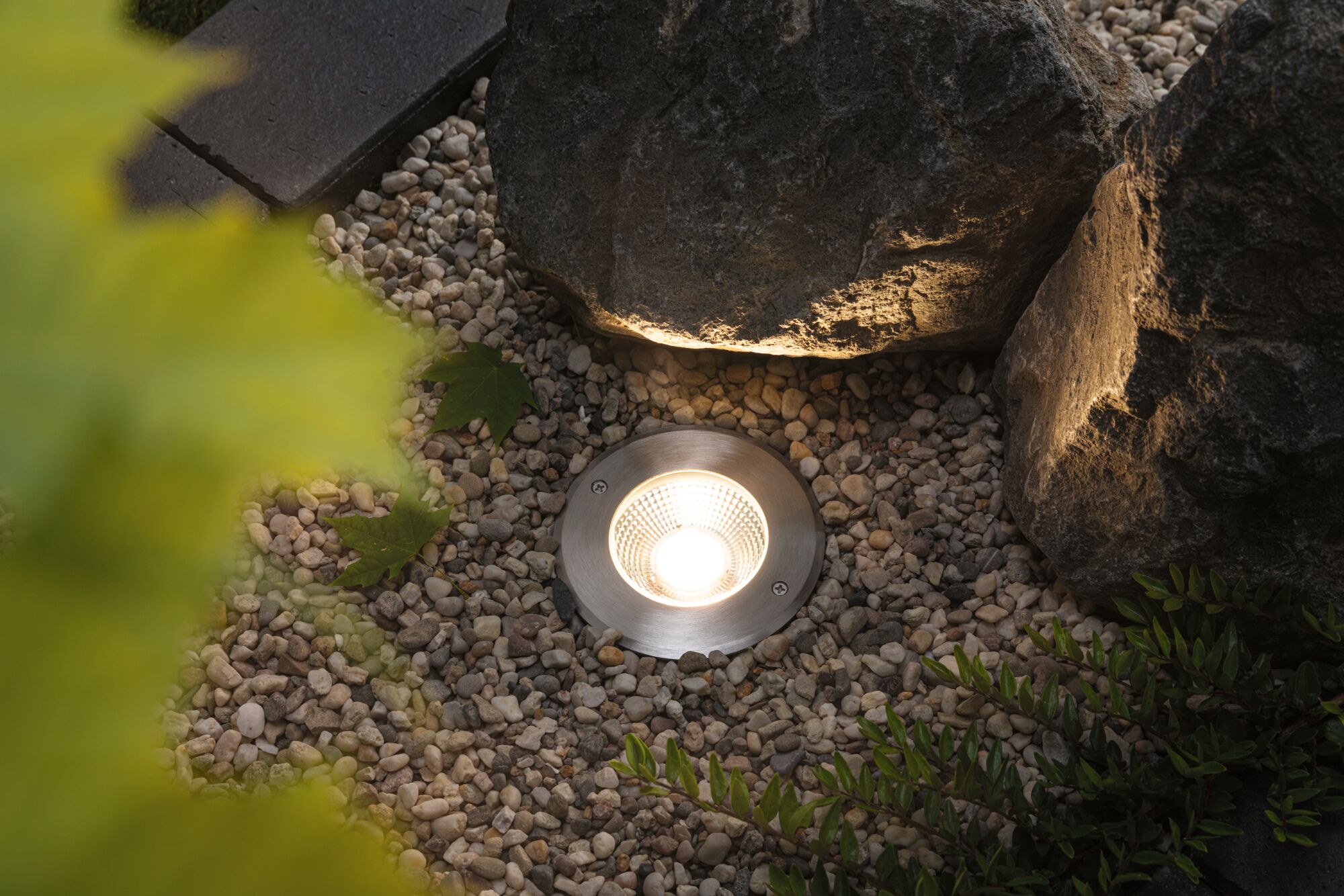 Recessed stainless steel garden light with warm white LED between gravel and rocks