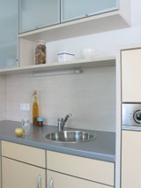 Moderne Küchenzeile mit Edelstahl-Spüle, grauer Arbeitsplatte und hellen Schrankfronten im minimalistischen Stil