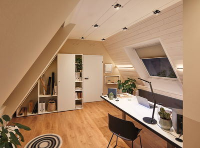 Chambre mansardée moderne avec bureau blanc, chaise noire et éclairage minimaliste pour bureau à domicile.