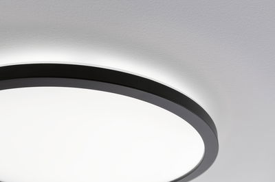 Rund loftlampe med sort aluminiumsramme og hvid diffuser til moderne indendørs belysning