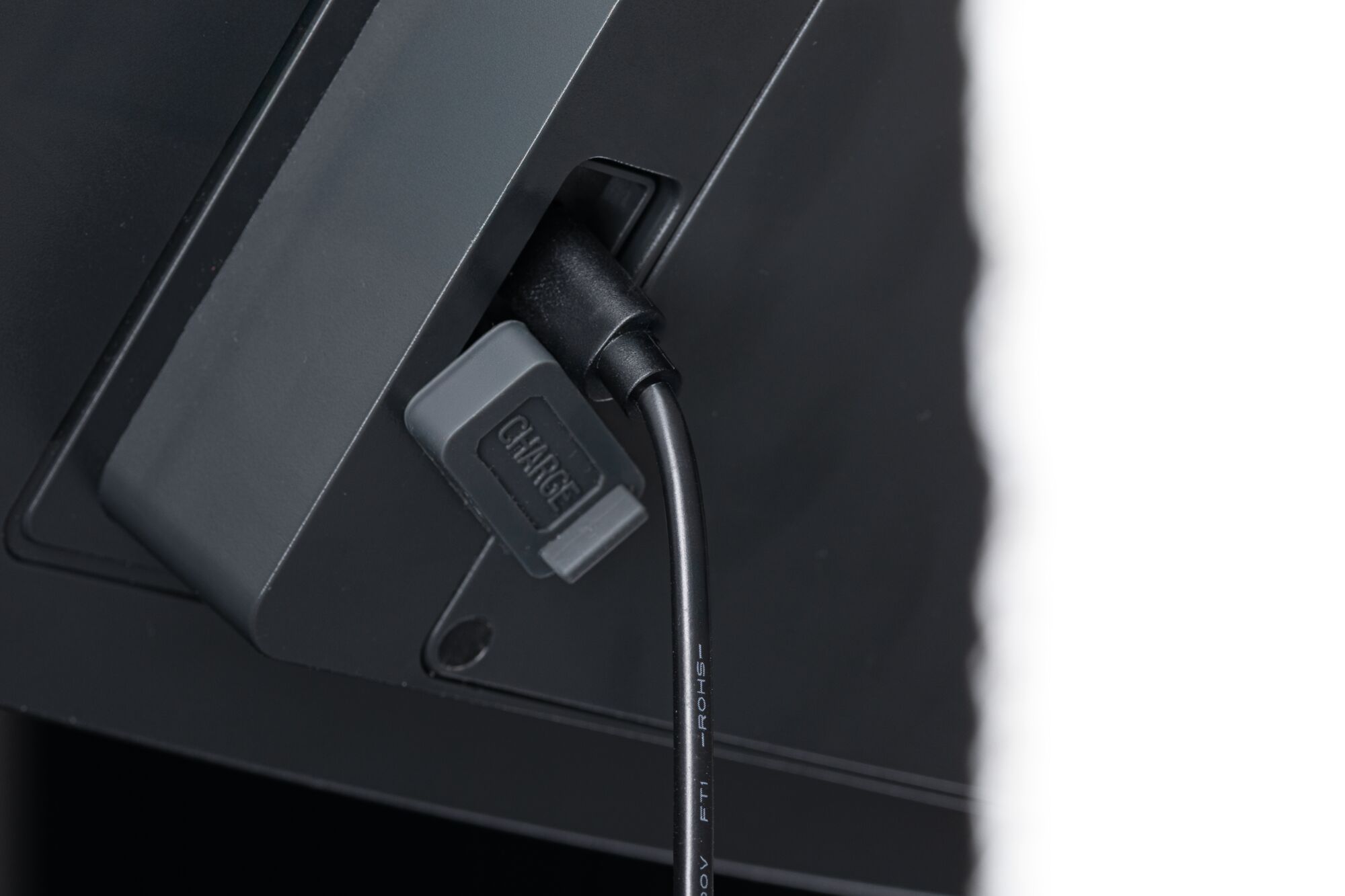 Câble de charge noir avec protection grise connecté à un appareil électronique noir