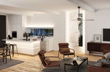 Salon moderne avec fauteuils en tissu marron, sol en bois et îlot de cuisine blanc avec éclairage LED