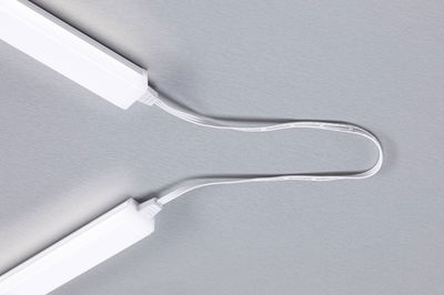 Zwei weiße LED-Leuchtleisten verbunden durch ein weißes Kabel auf grauem Hintergrund, LED-Beleuchtung Zubehör