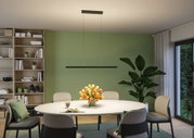 Black metal LED pendant light above round dining table with flowers and green wall