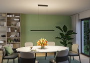 Schwarze LED-Pendelleuchte aus Metall über rundem Esstisch mit Blumenstrauß und grüner Wand