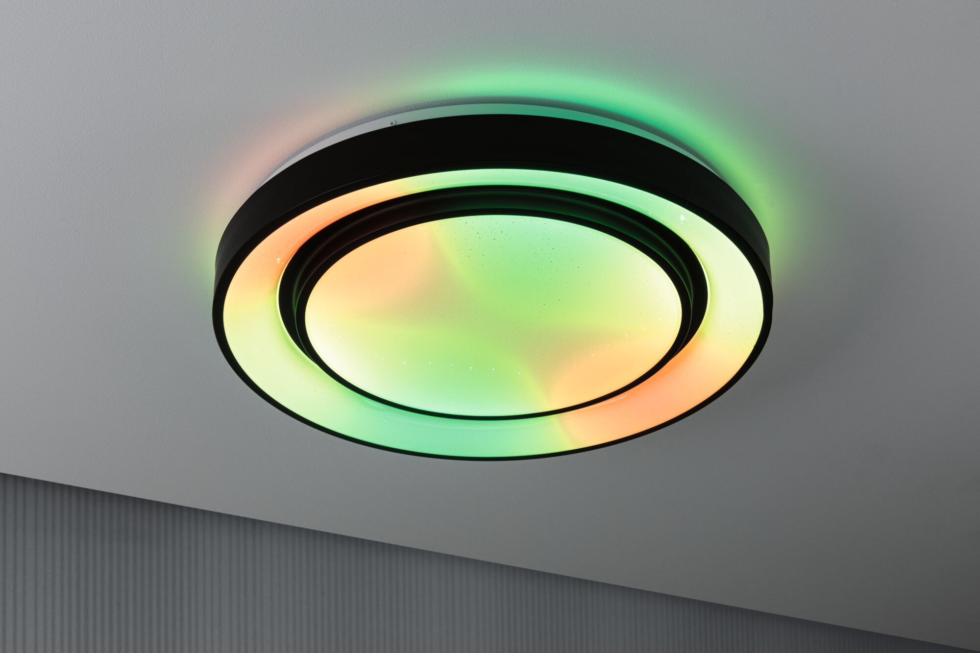 Runde LED-Deckenleuchte mit schwarzem Rahmen und mehrfarbigem Licht für moderne Wohnräume.