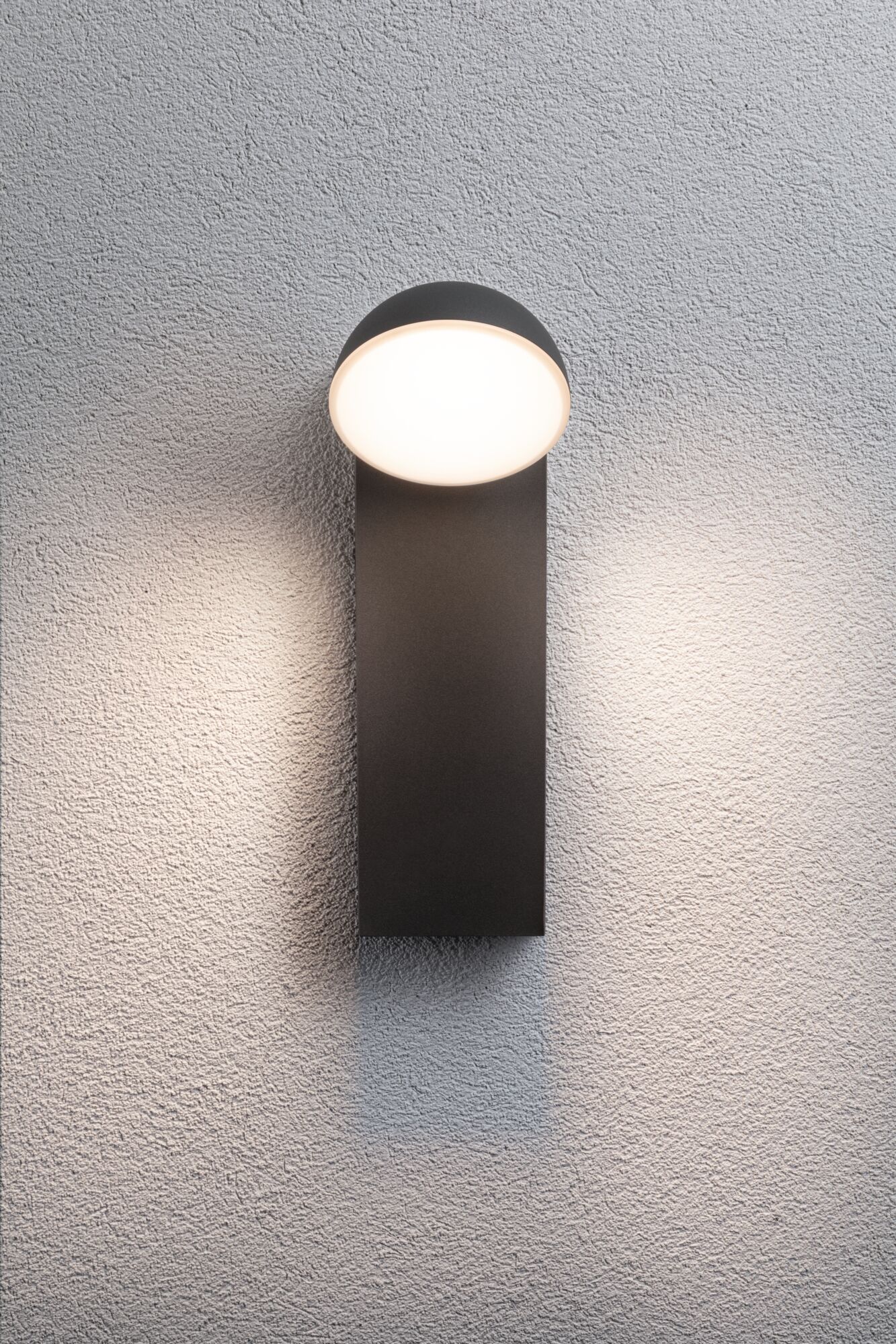 Modern black wall light with round white diffuser on textured wall, LED outdoor lighting fixture