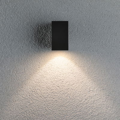 Black rectangular metal LED wall light with warm white illumination on textured wall