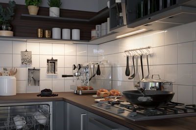 Cuisine moderne avec éclairage LED sous meuble, machine à café en acier inoxydable et poêle noire sur cuisinière à gaz.