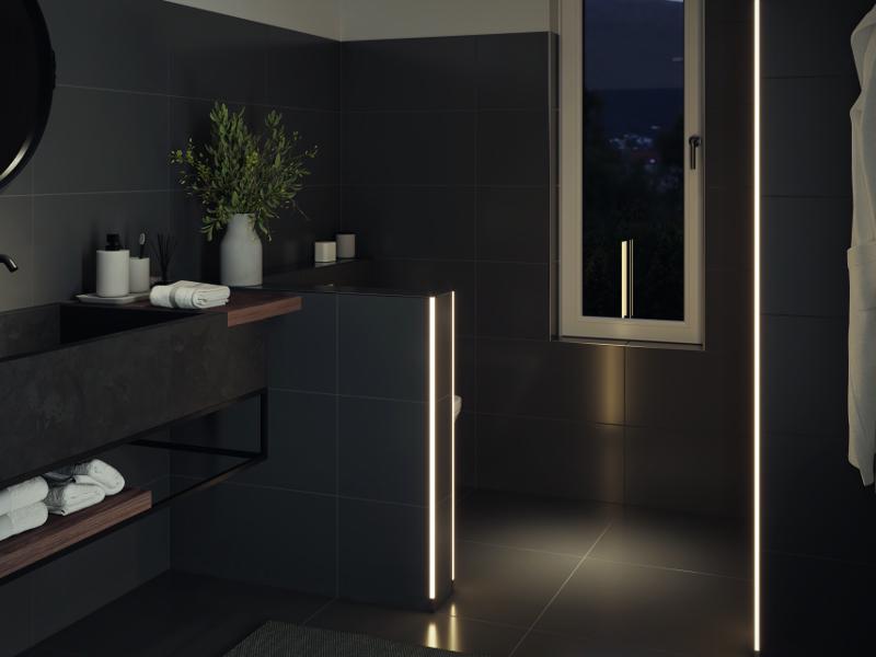 Modernes Badezimmer mit schwarzen Fliesen und warmweißen LED-Lichtleisten für stimmungsvolle Beleuchtung.