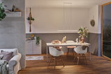 Salle à manger moderne avec table blanche, chaises en bois et suspension LED minimaliste à lumière chaude.