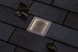 Eingelassene quadratische LED-Bodenleuchte aus Edelstahl mit warmweißem Licht auf dunklem Pflaster
