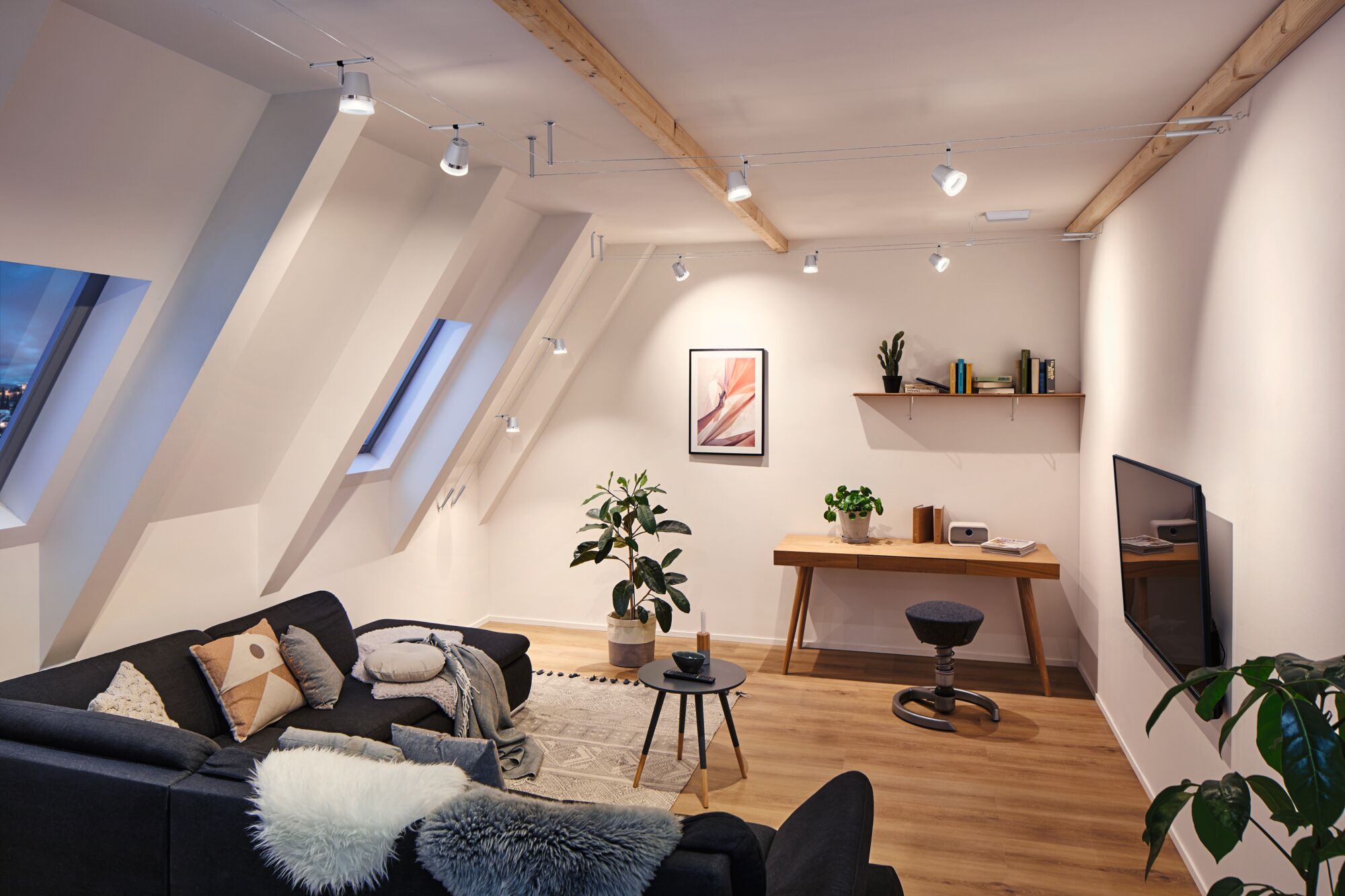 Salon moderne avec canapé noir, sol en bois et spots LED blancs suspendus au plafond pour éclairage d'accent
