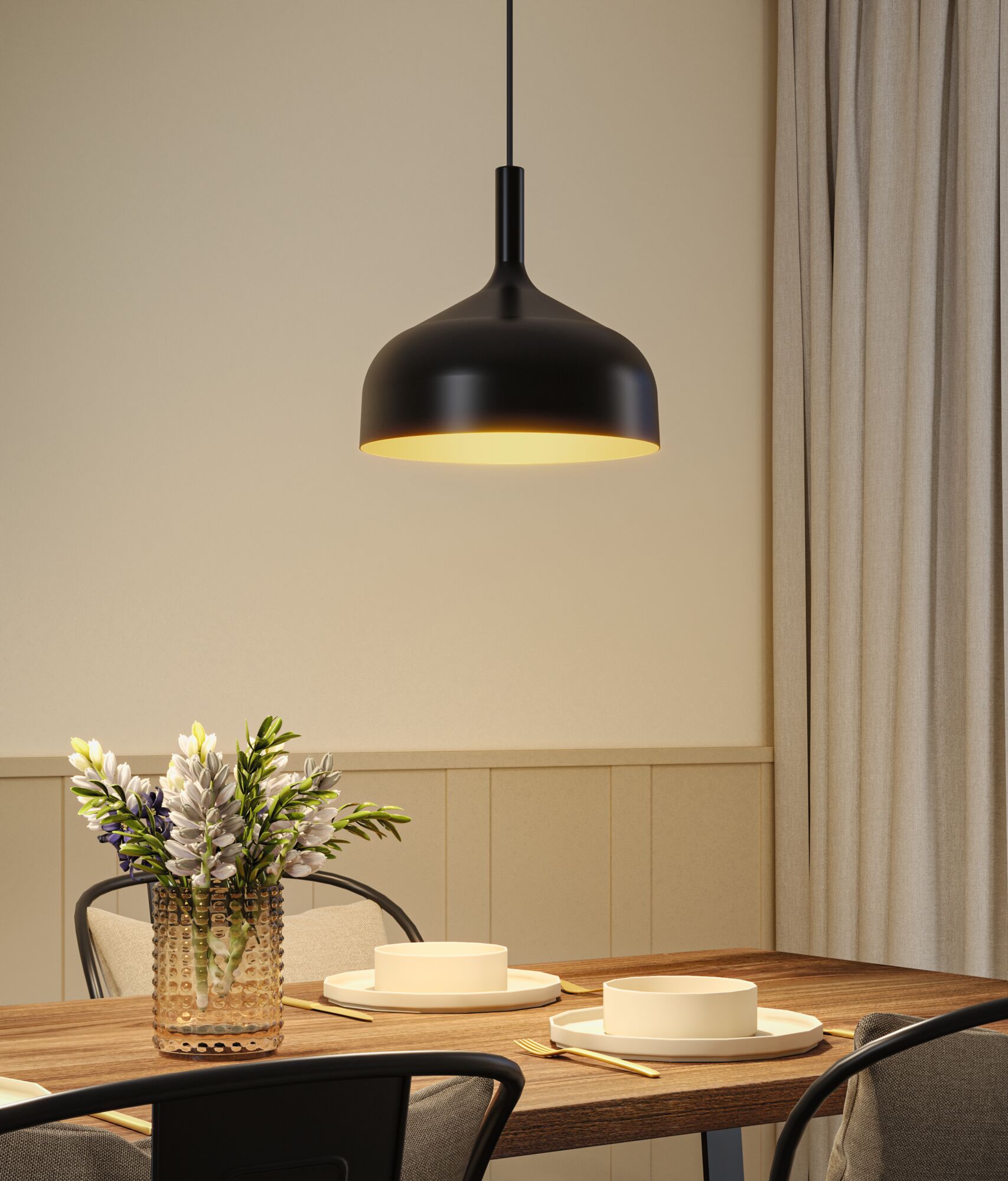 Black metal pendant lamp with warm light above wooden table set with plates and flower vase