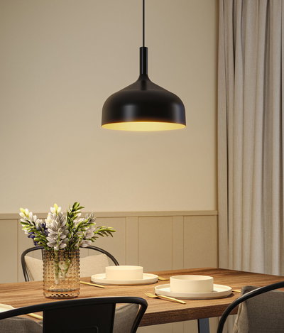 Black metal pendant lamp with warm light above wooden table set with plates and flower vase
